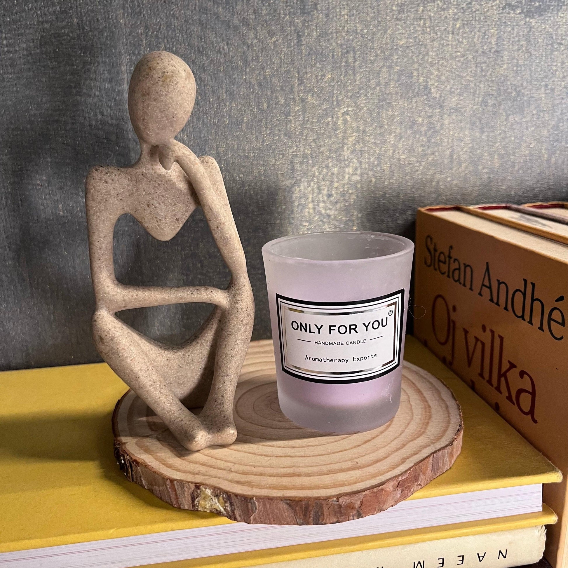 ceramic figurine next to a mini scented candle on a wooden plate as home decoration